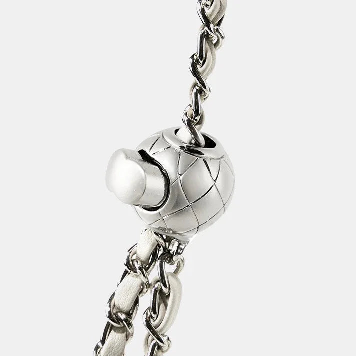 Close-up of quilted silver bag clasp with leather and chain strap on white background