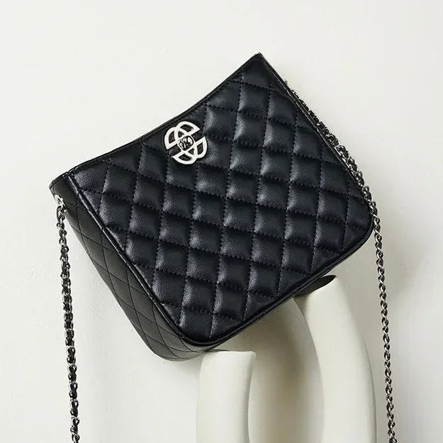 Black quilted leather crossbody bag with silver chain strap and metal logo on display