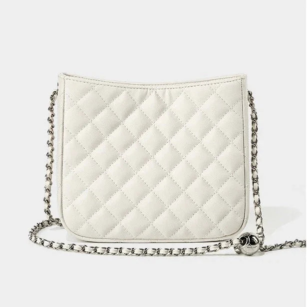 White quilted crossbody bag with silver chain strap on plain background