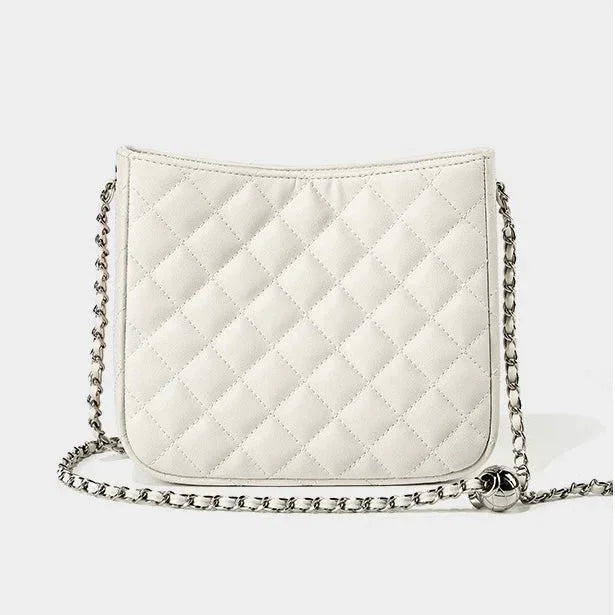 White quilted crossbody bag with silver chain strap on plain background