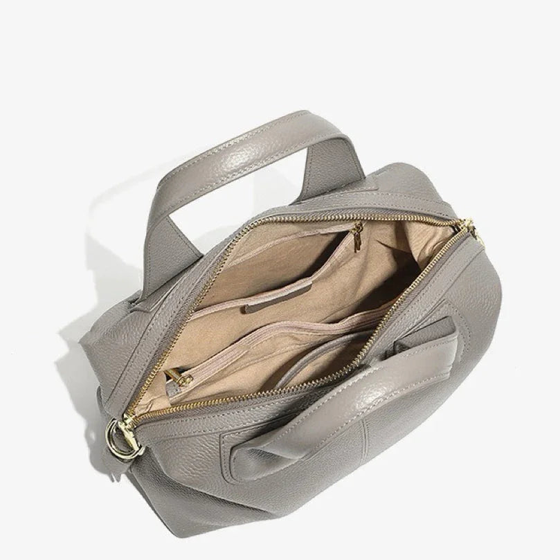 Open gray leather handbag with top handles, gold zipper, and beige fabric lining
