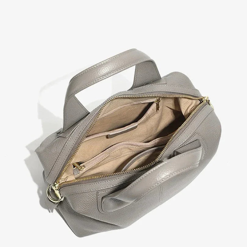 Open gray leather handbag with top handles, gold zipper, and beige fabric lining
