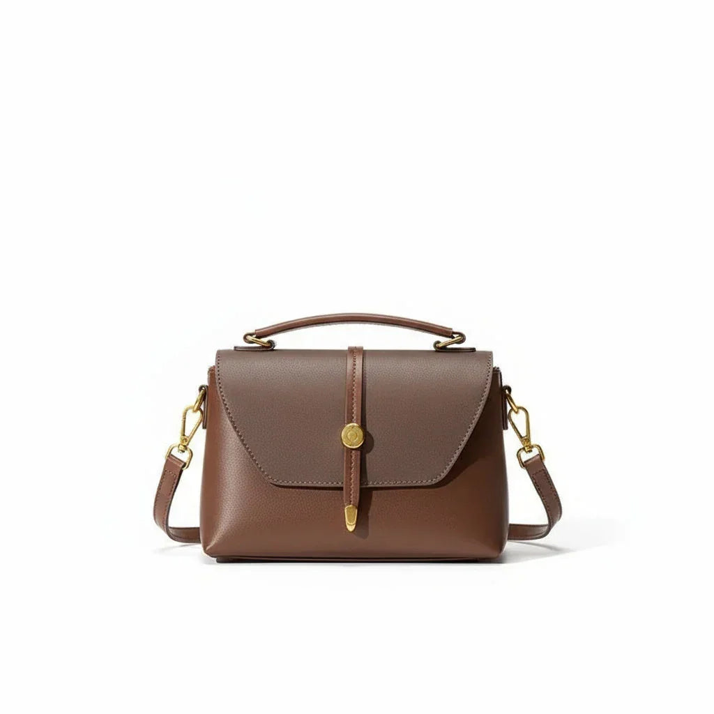 Brown leather satchel handbag with top handle and gold hardware on white background
