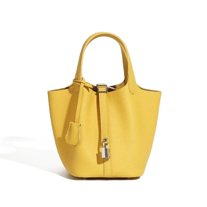 Yellow leather bucket bag with top handles and silver lock on a white background