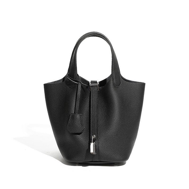 Black textured leather tote bag with top handles and silver lock against white background