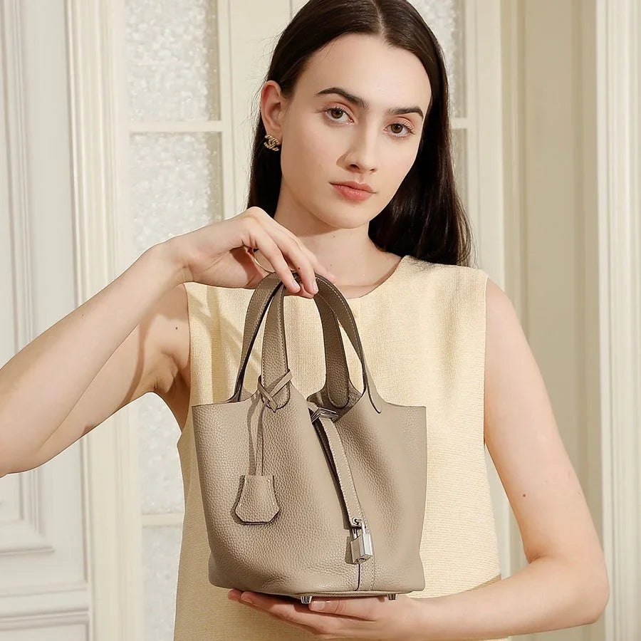 Woman holding beige leather tote bag in elegant indoor setting