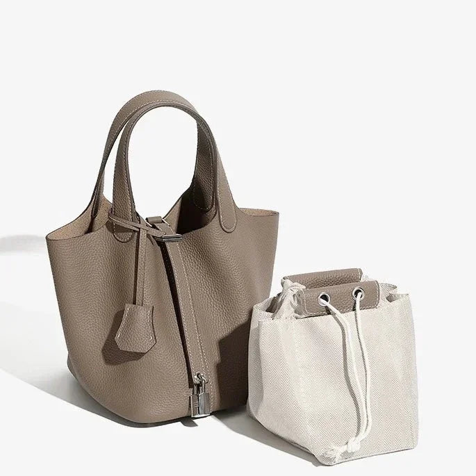 Taupe leather tote bag with top handles beside a white drawstring canvas pouch