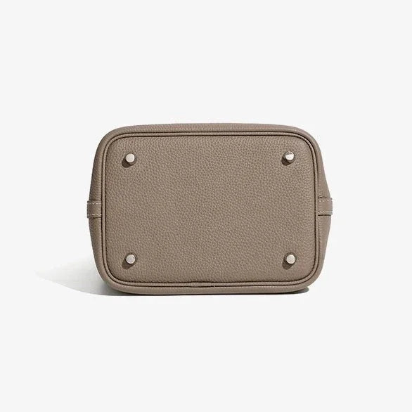 Beige pebbled leather handbag bottom with metal feet on white background