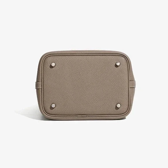 Beige pebbled leather handbag bottom with metal feet on white background