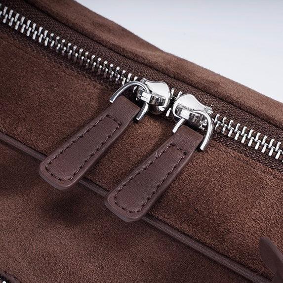 Closeup of brown suede bag with double zipper and leather zipper pulls