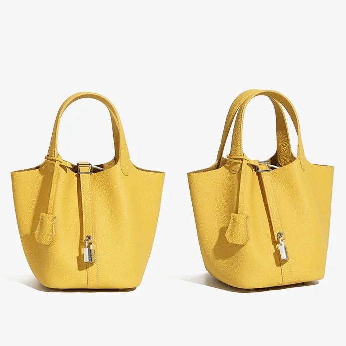 Two yellow leather tote handbags with lock detail on white background