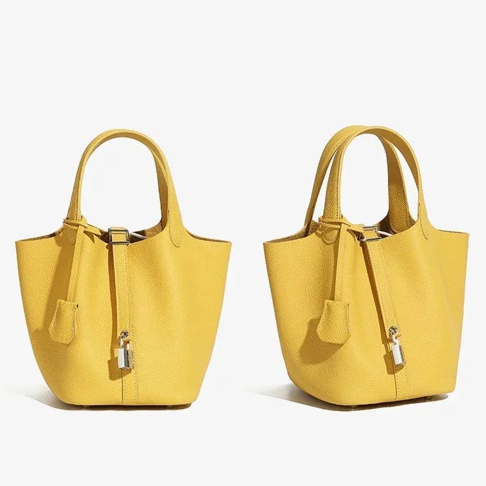 Two yellow leather tote handbags with lock detail on white background