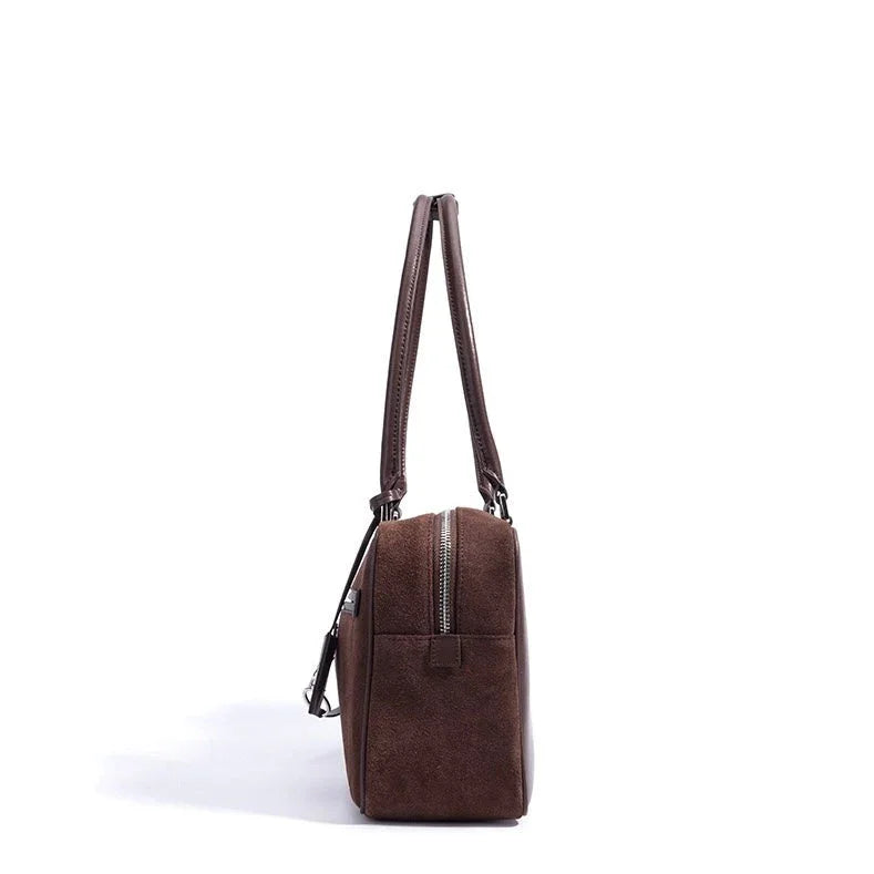 Side view brown leather tote bag with zipper and double handles on white background