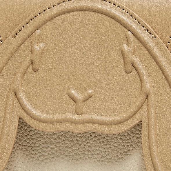 Embossed bunny face on textured tan leather bag close-up