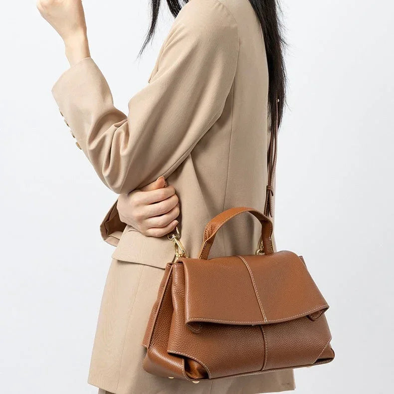Woman in beige blazer carrying a brown leather handbag with top handle and shoulder strap
