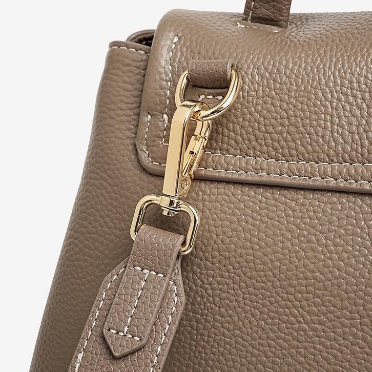 Taupe leather handbag with gold hardware and stitched strap close-up