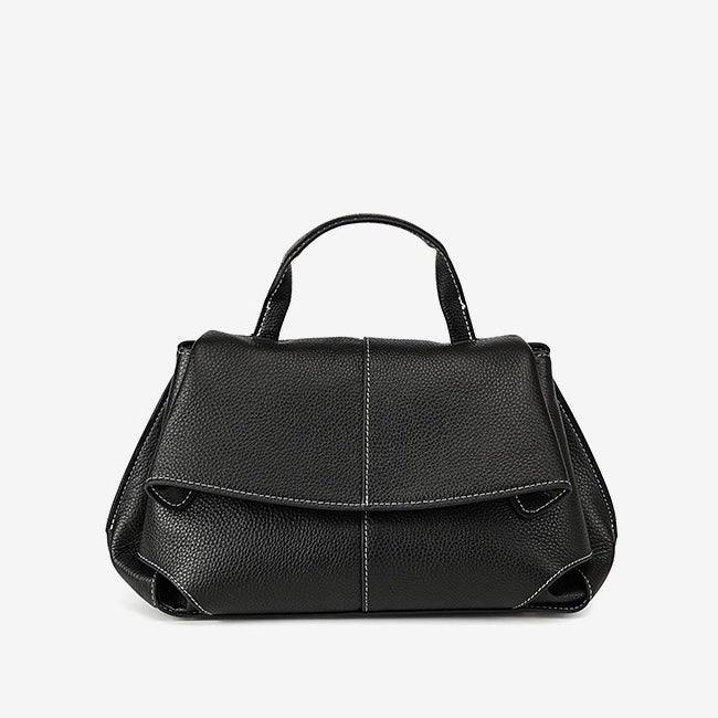 Black leather handbag with top handle, textured finish, and white stitching on white background