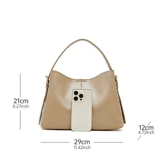 Beige leather handbag with top handle, phone for scale, bag dimensions labeled in cm and inches