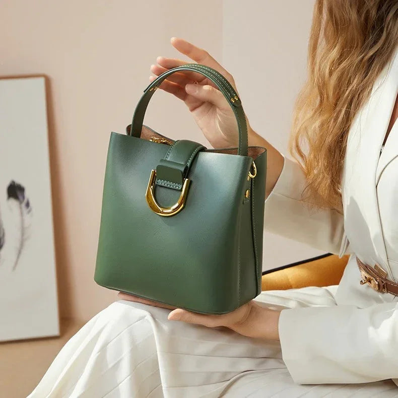 Woman in white suit holding green leather handbag with gold hardware indoors