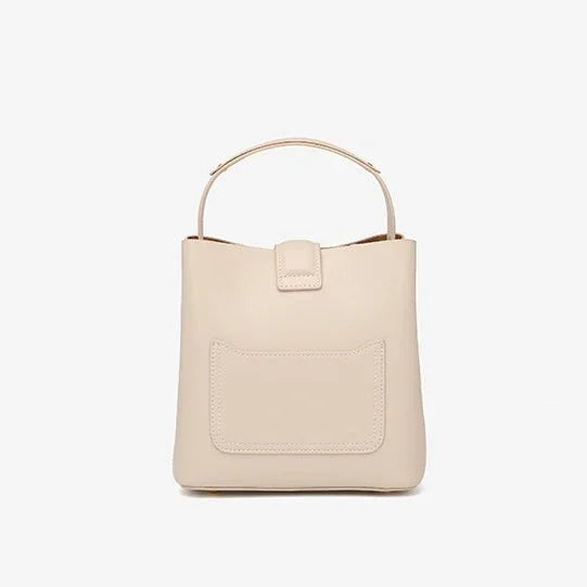 Beige leather handbag with top handle and front pocket against white background