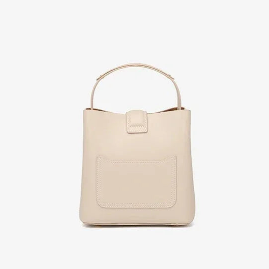 Beige leather handbag with top handle and front pocket against white background