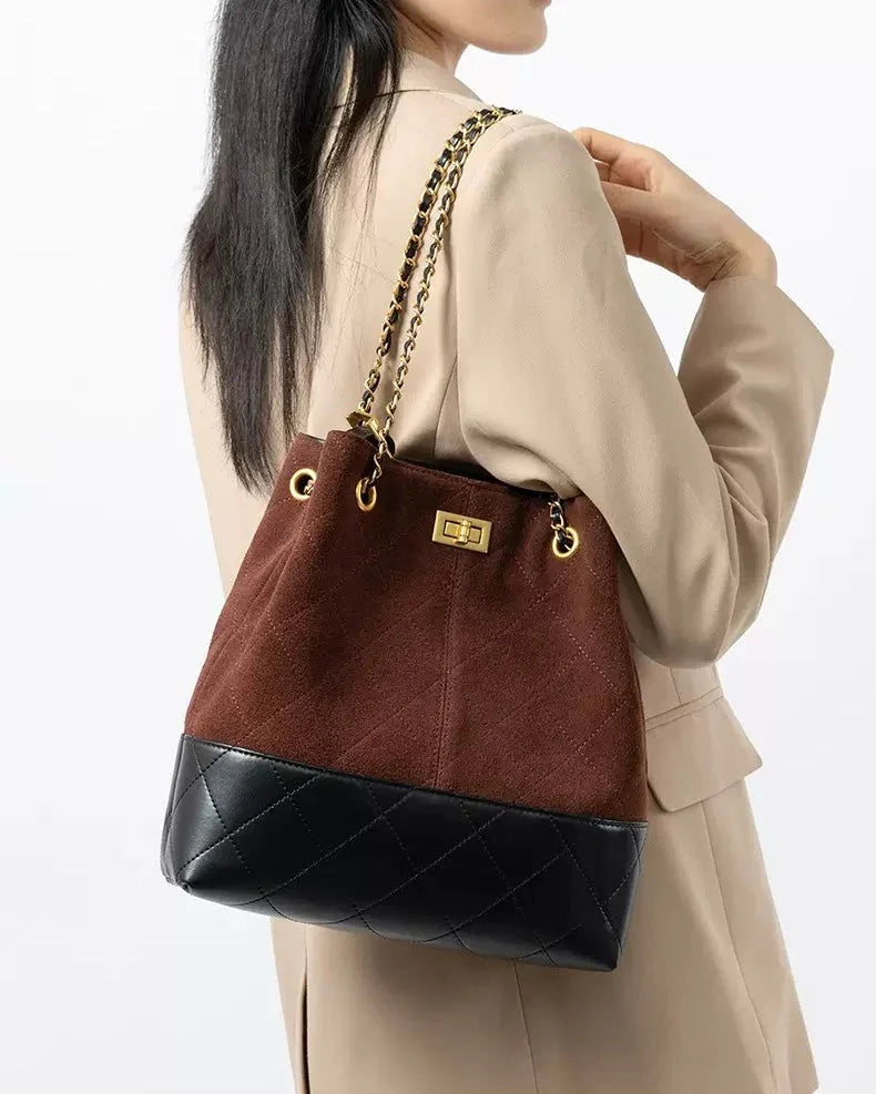 Woman in beige blazer with brown and black quilted bucket bag, gold chain strap