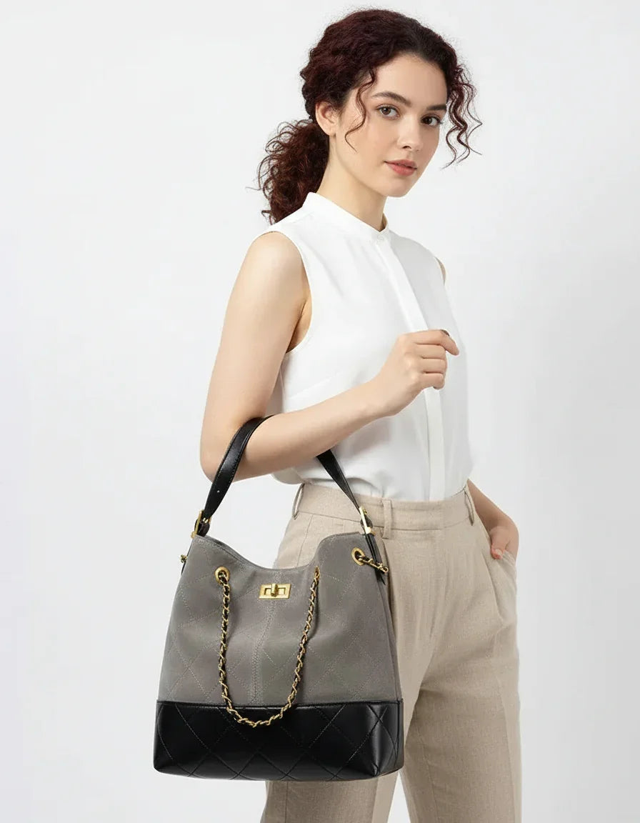 Woman holding gray and black quilted leather handbag with gold chain handle