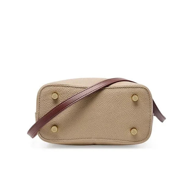 Beige leather crossbody bag with gold feet and brown strap on white background