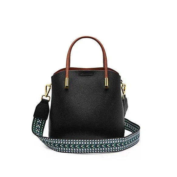 Black leather handbag with brown handles and a patterned detachable shoulder strap