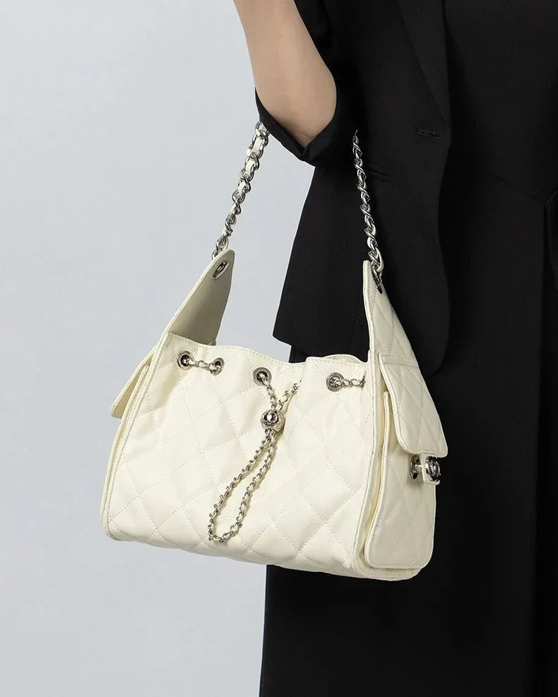 Woman holding quilted white shoulder bag with chain strap and silver hardware