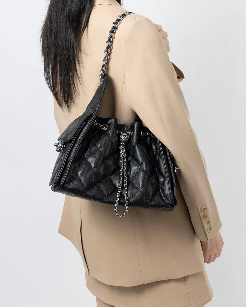 Woman in beige blazer carrying a black quilted leather shoulder bag with chain strap
