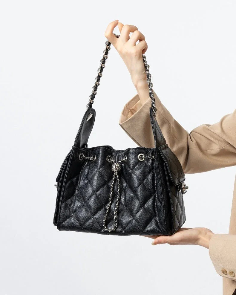 Woman holding black quilted leather handbag with chain strap and silver hardware