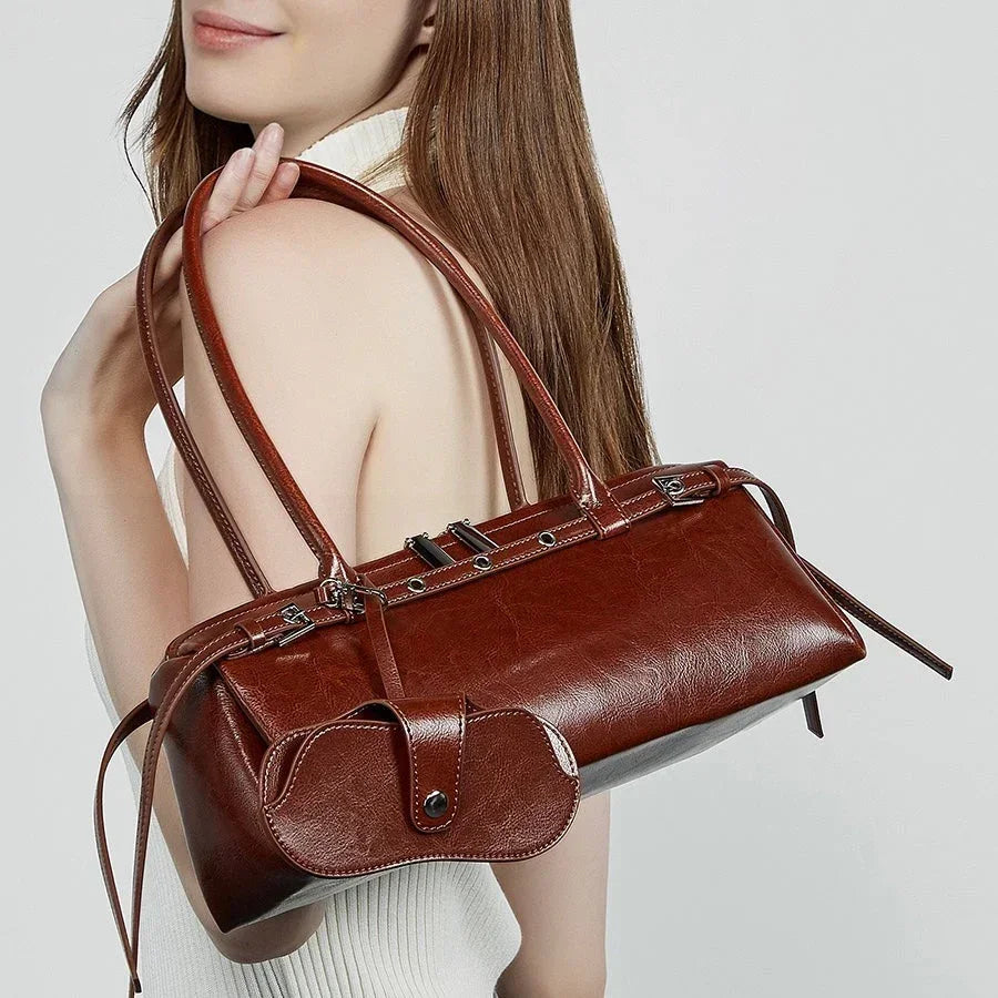 Woman holding brown leather handbag with mini pouch on shoulder, fashion accessory