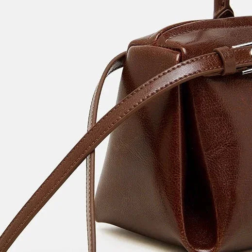 Brown leather crossbody bag with long strap on white background
