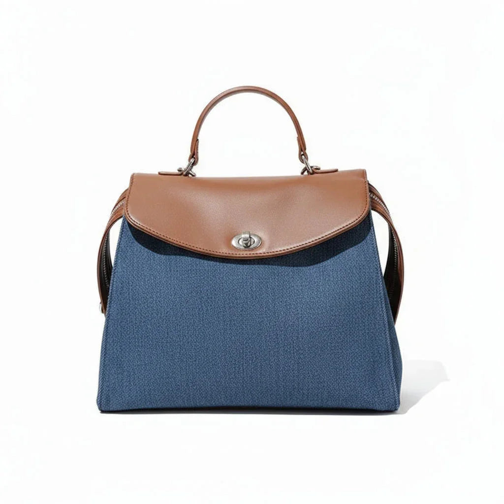 Blue handbag with brown leather flap and handle on white background