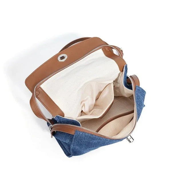 Open blue denim and tan leather handbag showing spacious interior with pockets