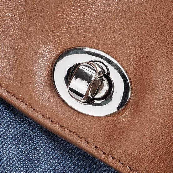 Close-up of a silver turn-lock clasp on a brown leather purse with denim background
