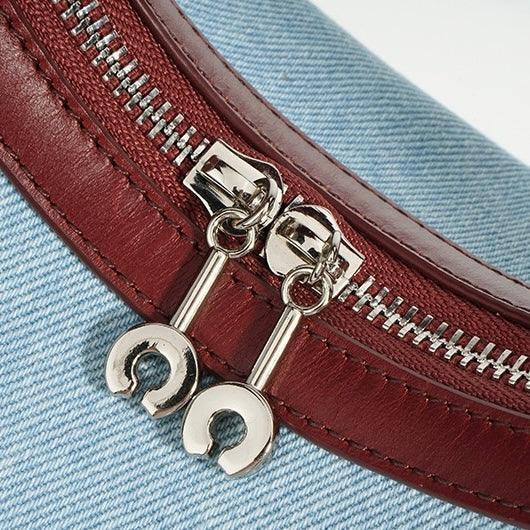 Close-up of silver zipper on blue denim and red leather bag