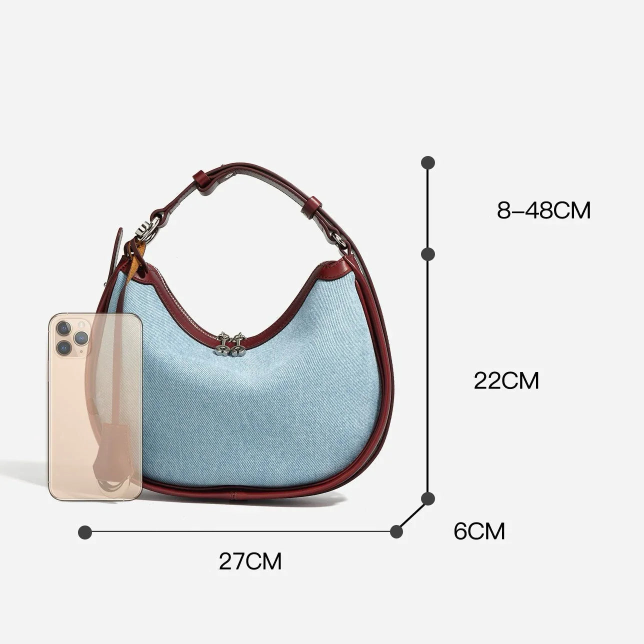 Light blue denim handbag with brown leather trim and handle, shown with dimensions and a smartphone for size reference.