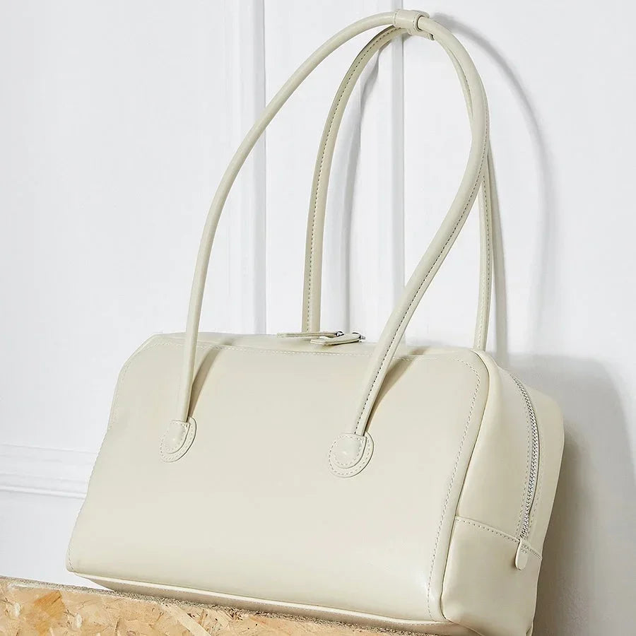 Cream leather handbag with double handles on a light background