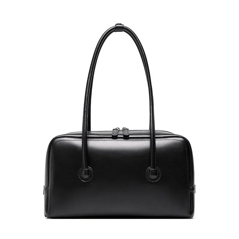 Black leather handbag with double handles and zip closure on white background