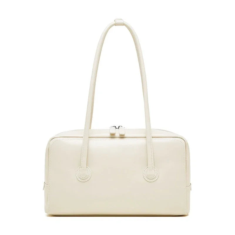 Cream rectangular leather handbag with double handles and zip closure on white background