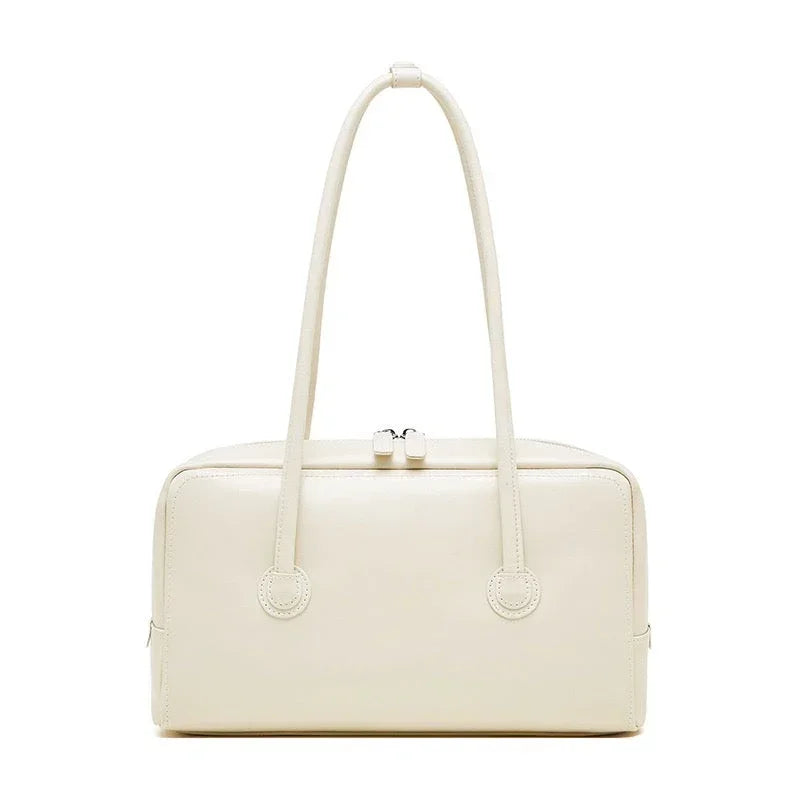 Cream rectangular leather handbag with double handles and zip closure on white background