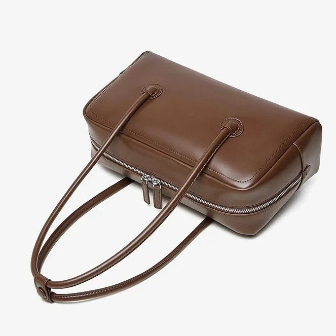 Brown leather tote bag with double handles and zipper closure on a white background