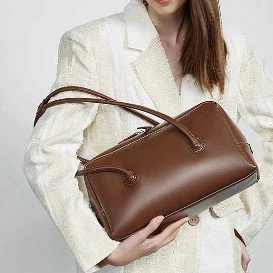 Woman in white blazer holding large brown leather handbag