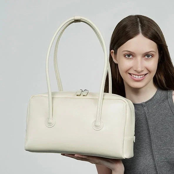Woman holding a cream leather handbag with double handles, fashion accessory product