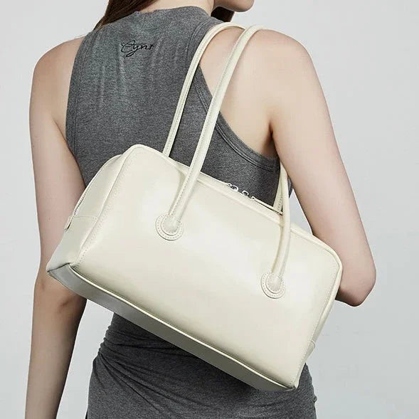 Woman in gray sleeveless top carrying a white leather shoulder bag
