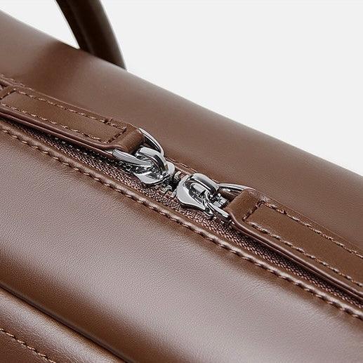 Close-up of brown leather bag with silver zipper on white background