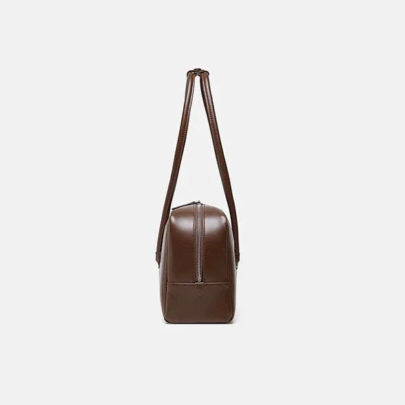 Side view of brown leather tote bag with long shoulder straps on white background
