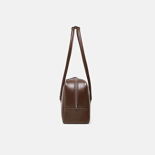 Side view of brown leather tote bag with long shoulder straps on white background
